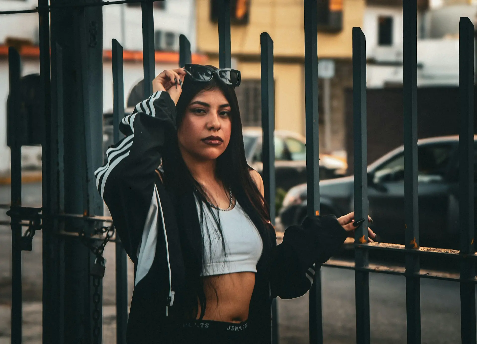 A woman is standing behind a fence with her hand on her head